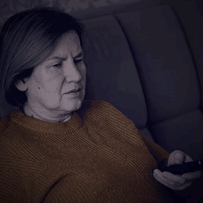 A woman sitting in front of the TV in the evening
